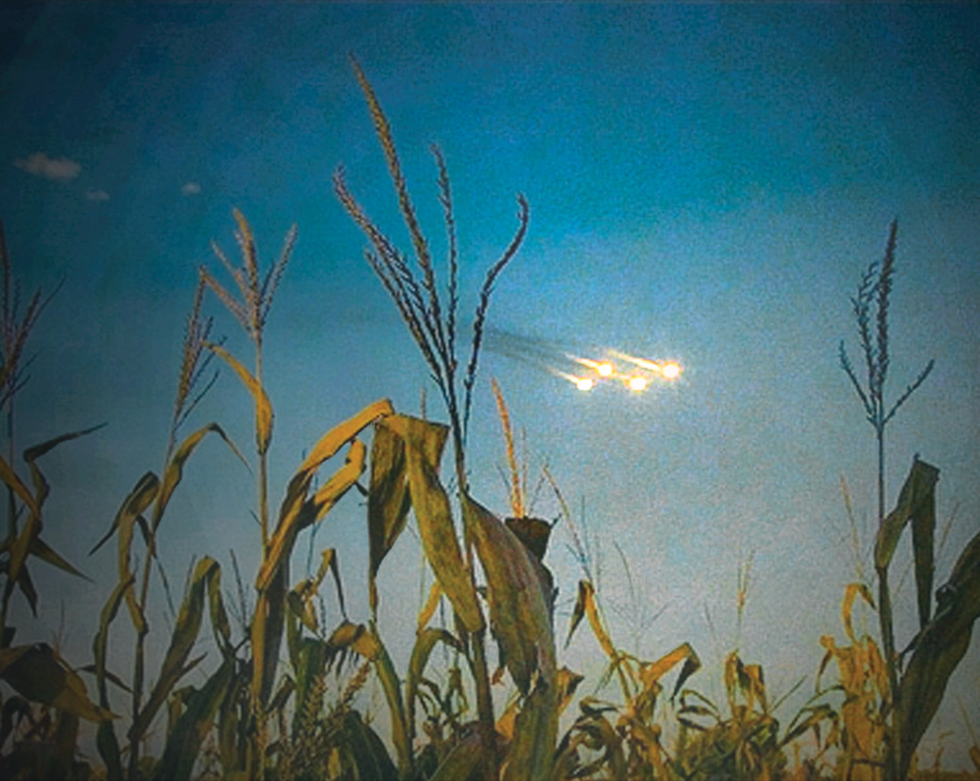Oliver Wasow’s two thousand and nine artwork “Hallucination (Wisconsin).” It depicts some kind of possibly alien space crafts in the sky above a cornfield.