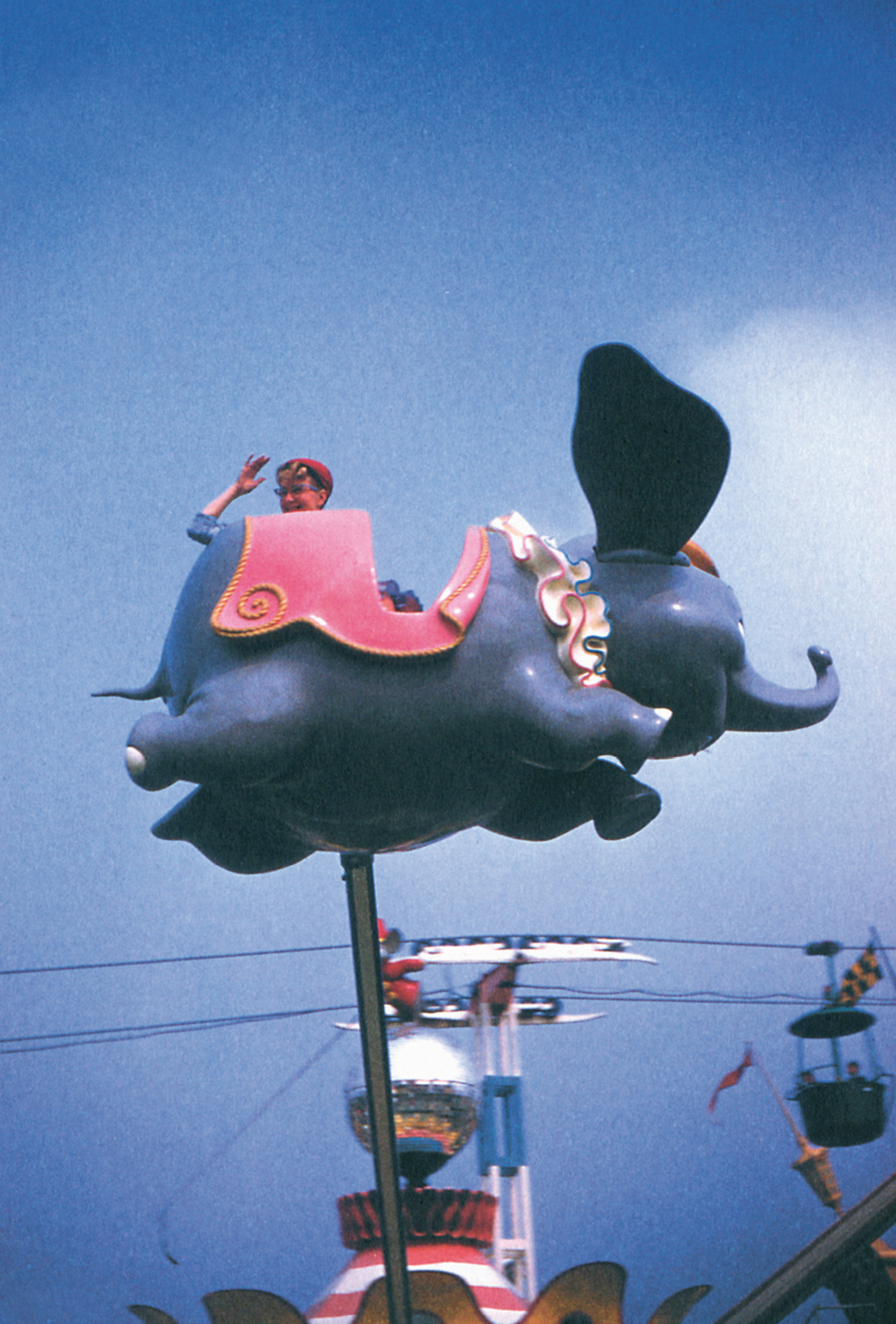 A photograph of a woman on a Dumbo ride at an amusement-park.