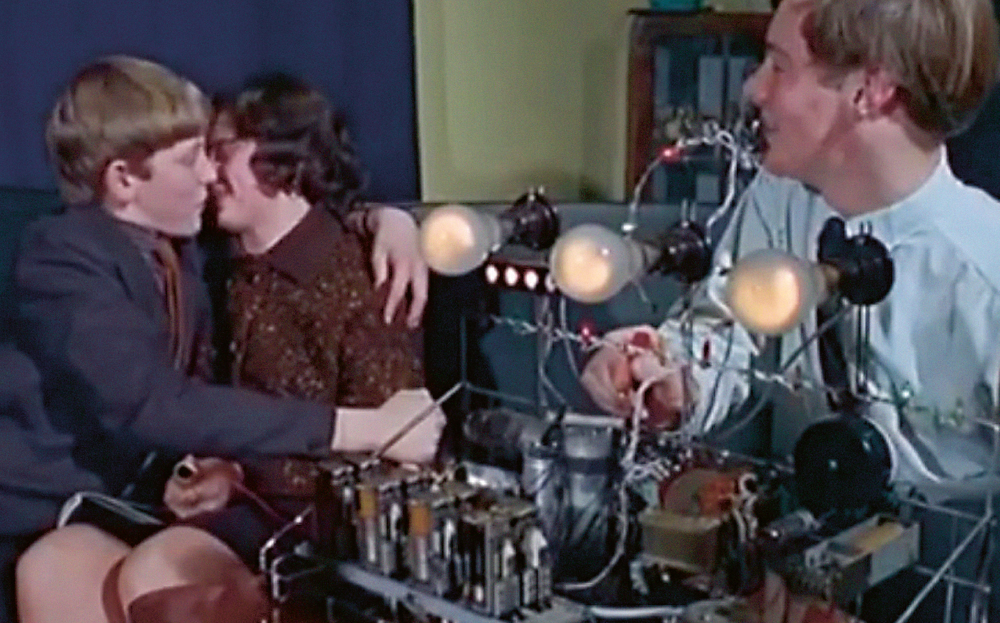 Still from 1965 British Pathé newsreel featuring the Snogometer, an invention of sixteen-year-old Malcolm Pickard (at right, manning the apparatus) designed to measure the electrical resistance between a couple engaged in “passionate mashing.”