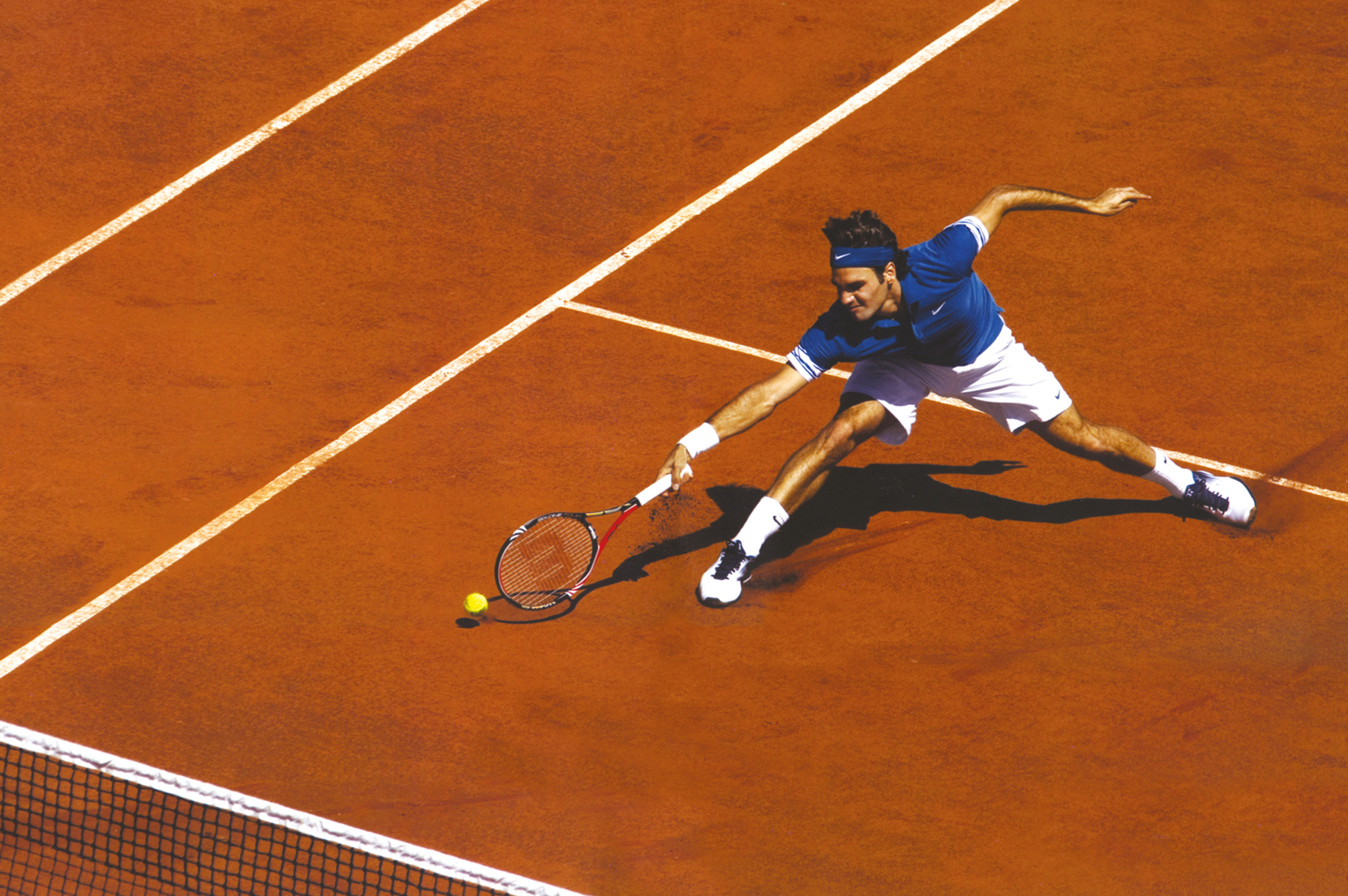 A photograph of Federer diving for the ball at the two thousand and ten French Open.