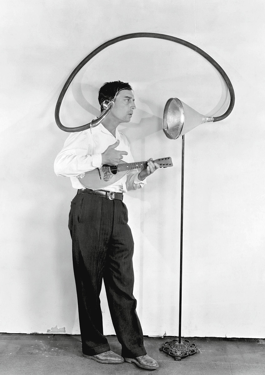 A photograph from the late nineteen twenties of Keaton listening to his own voice using a trumpet-like machine.