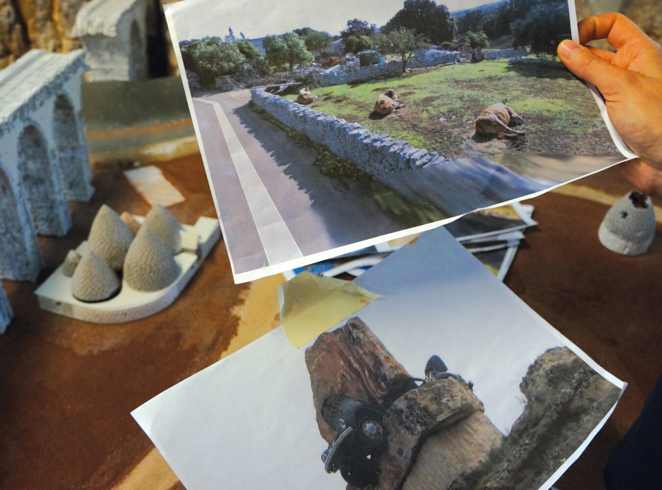 A photograph of a model-maker at the Miniatur Wunderland examining photographs of landscapes.