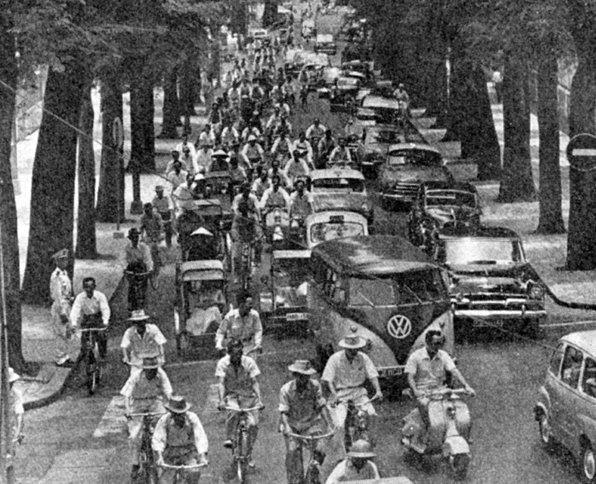 A photograph showing cars, bicycles, and rickshaws in rush hour traffic on the Rue Pasteur in Saigon.