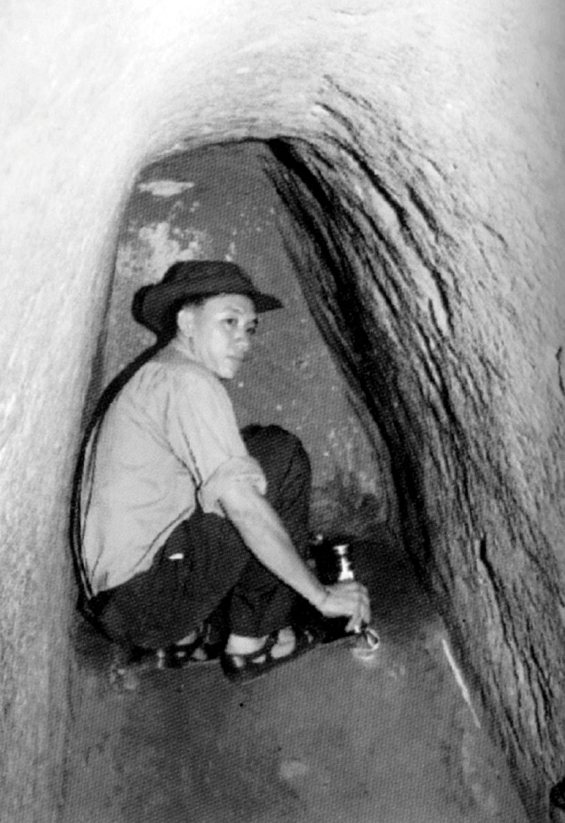 A photograph of a man crouching in one of the Cu Chi Tunnels, Ho Chi Minh City. From a 1992 guidebook published in Vietnam entitled “Thanh pho HCM tu gioi thieu.”