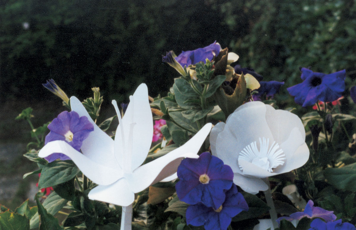 A photograph of paper flowers made by artist Rachel Urkowitz inserted into the gardens at Giverny.
