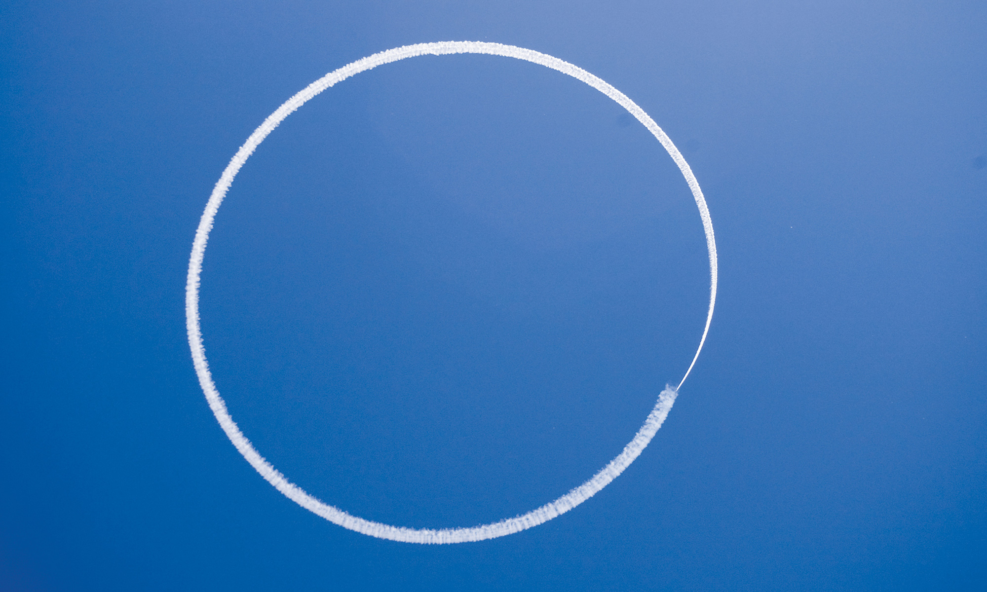 A photograph of a circular smoke signal against a blue sky.