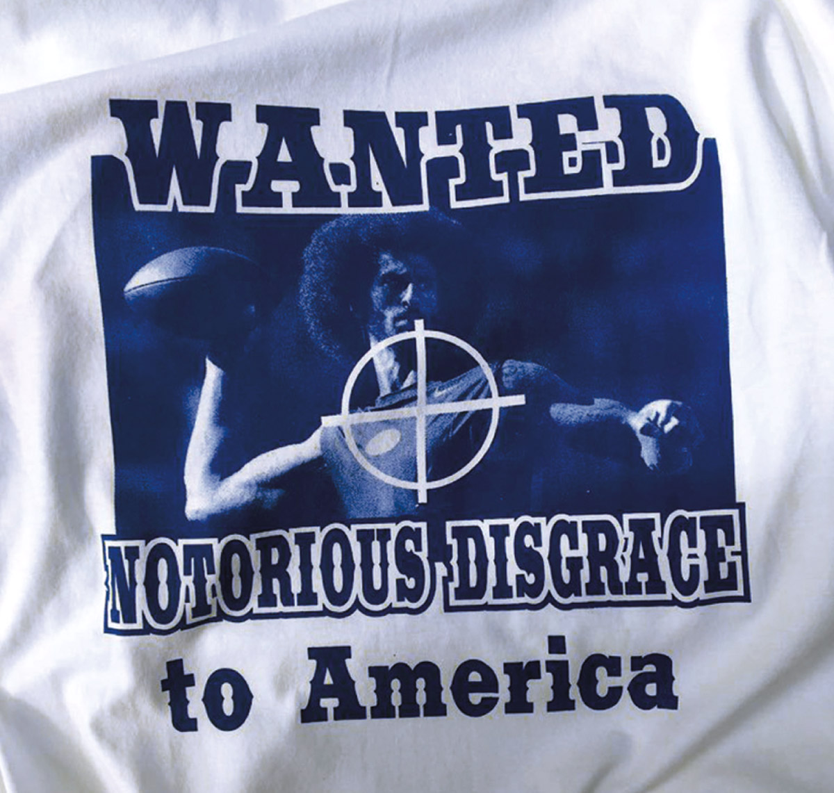A photograph of a tee shirt with an image of a rifle crosshair design targeting Colin Kaepernick. The shirt was for sale outside the Buffalo Bills stadium when the team hosted the San Francisco Forty Niners on October sixteenth twenty sixteen.