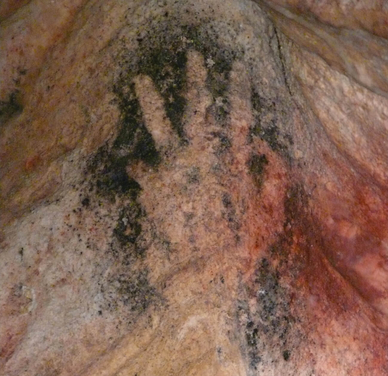 An image of a cave painting, circa twenty five thousand BC, depicting the shape of a human hand. The painting is located near the town of Gargas in the Luberon area of France, which is also home to a number of mines that produce sienna.