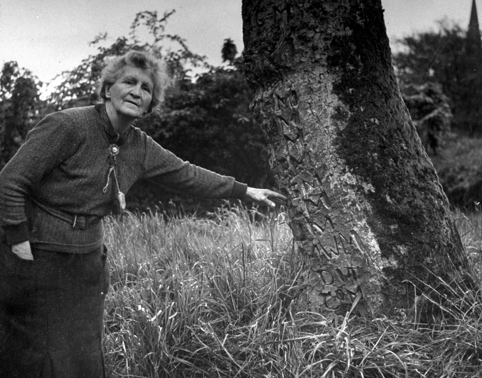A nineteen forty-three photograph of Lady Maud Montgomery showing off the initials of family members that were carved in a tree on her Moville, County Donegal estate in Ireland.