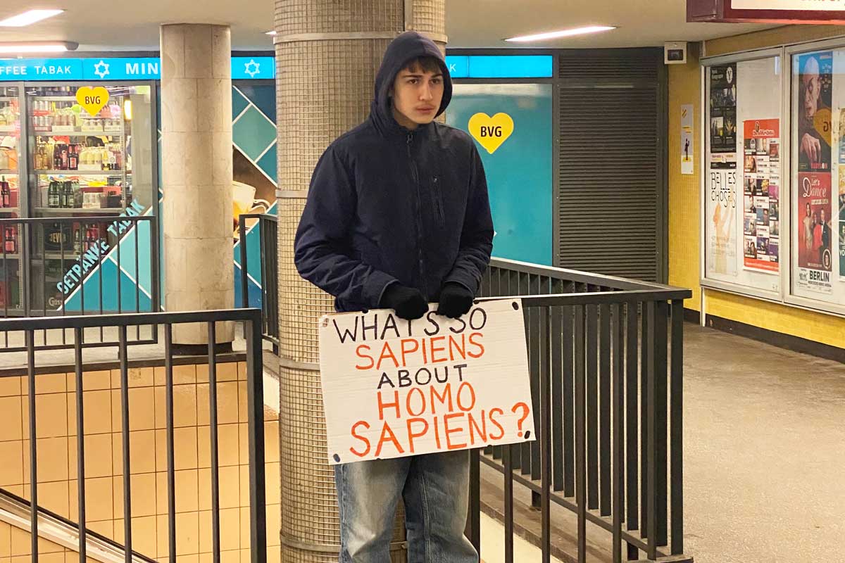 Photograph of a young man holding a sign in Berlin that reads 