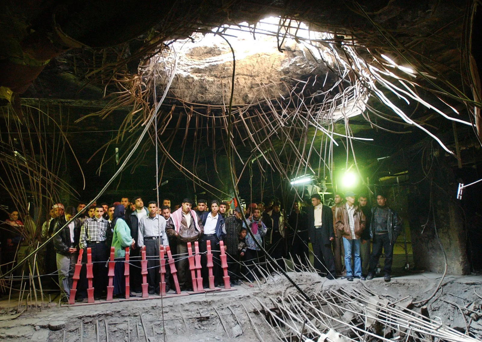 A two thousand and three photograph of Iraqi students visiting the Amiriyah bomb shelter and the crater made by United States bombs in nineteen ninety-one.