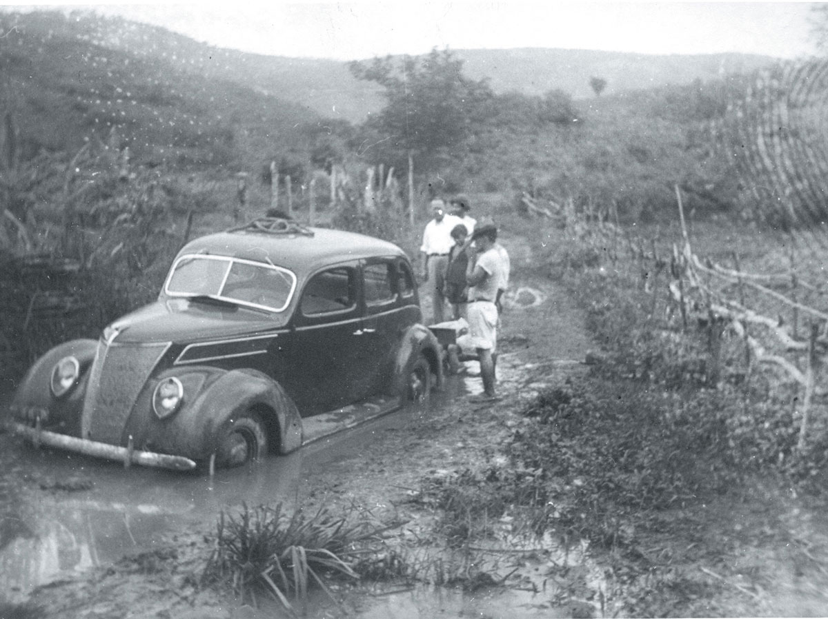 A photograph of an automobile stuck in the mud on the road to Fordlandia, circa 1940.