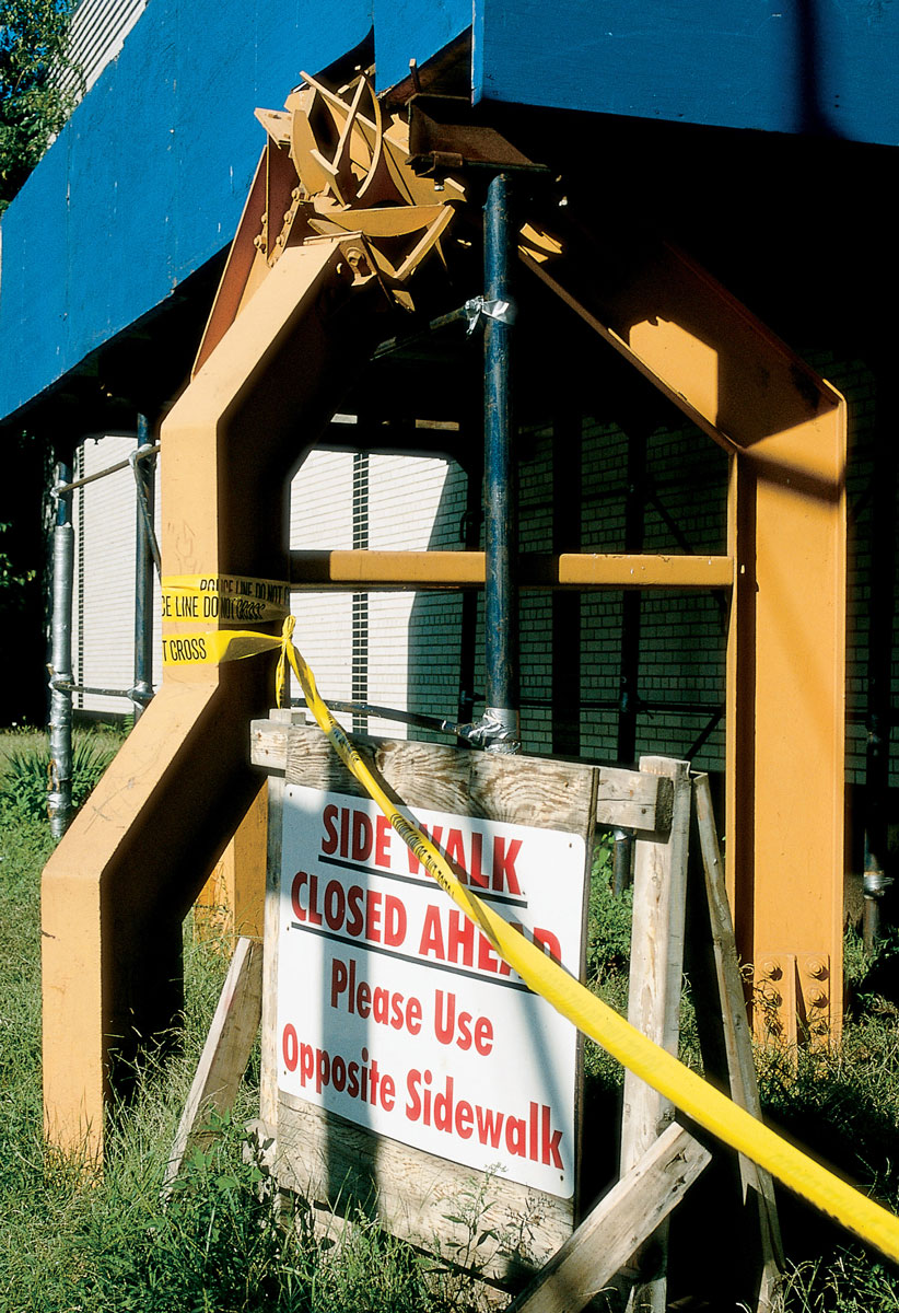 A photograph of Allen Mooney's sculpture Iroquois Walk wrapped in yellow caution tape.