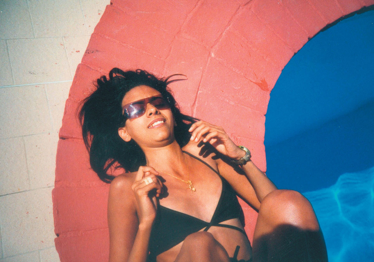 A Lomographic image depicting a woman in a bikini laying next to a pool.
